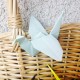 close up image of a white origami crane against a whicker basket