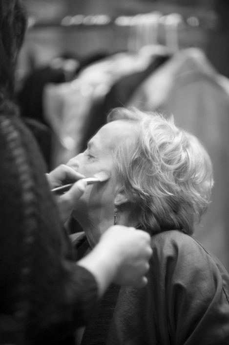 a black and white image of a woman having makeup applied using a makeup brush