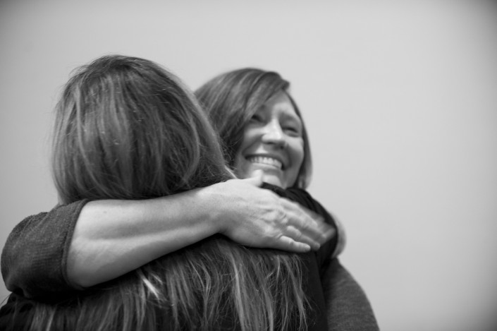 a black and white image of two women hugging each other with only one of their faces visible