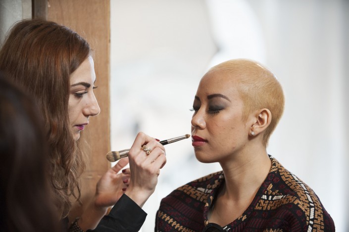 a woman with short hair getting her makeup applied by a woman with long hair