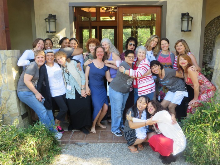 a large group of women posing for the camera and hugging each other