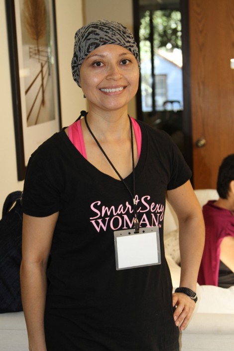 a woman in a black shirt with a scarf on her head and hand on her hip wearing a lanyard