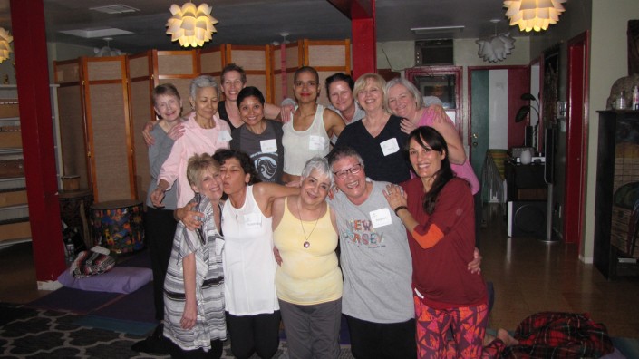 a group of women hugging and kissing cheeks while standing in a yoga studio room