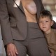 a young boy standing with a woman in a suit who is exposing one breast showing scars from surgery
