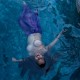 a woman wearing a purple skirt with her breasts exposed floating in a pool, seen from above
