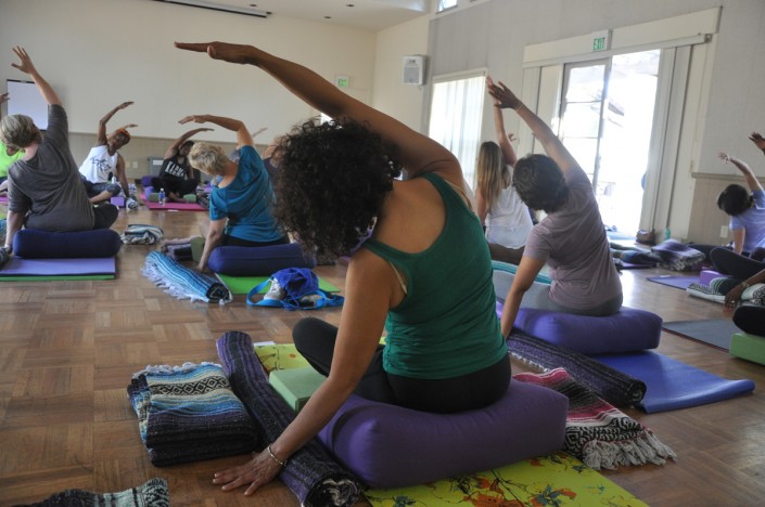 a group of women on yoga mats with one hand raised and leaning over to the side