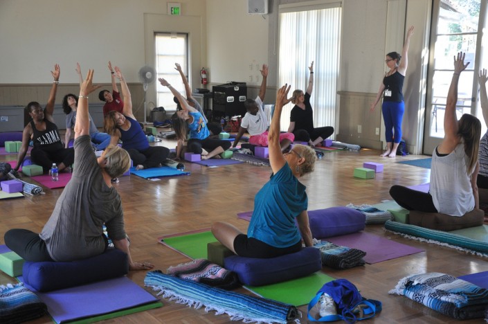 a group of women on yoga mats with one hand raised and the other hand on the floor providing balance