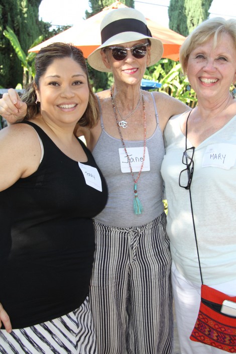 a woman in a gray outfit and white hat standing with her arms around a woman in a black tank and a woman in a white outfit