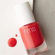 a bottle of red nail polish with a splash of polish on a white paper with a label reading rms