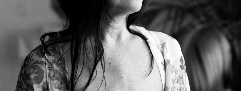 a black and white image of a woman wearing an open shirt and showing the scars of her surgery