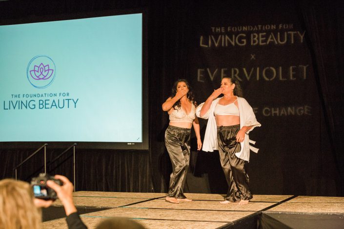 two women in white bras and black drawstring pants blowing kissed on a runway