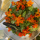 a bowl of salad with red flowers and tongs