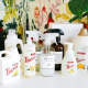 a collection of Thieves products in white bottles set on a table with a floral wallpaper background behind htem