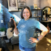 a woman in a blue living beauty t-shirt holding her hair that has just been cut