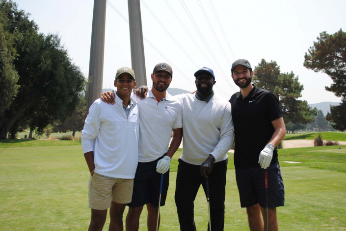 four men standing together on a golf course