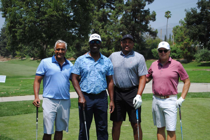 four men posing together on a golf course