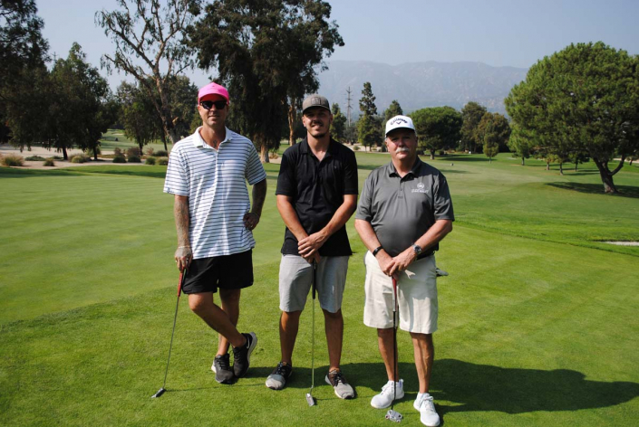 three men posing on a golf course with their golf clubs