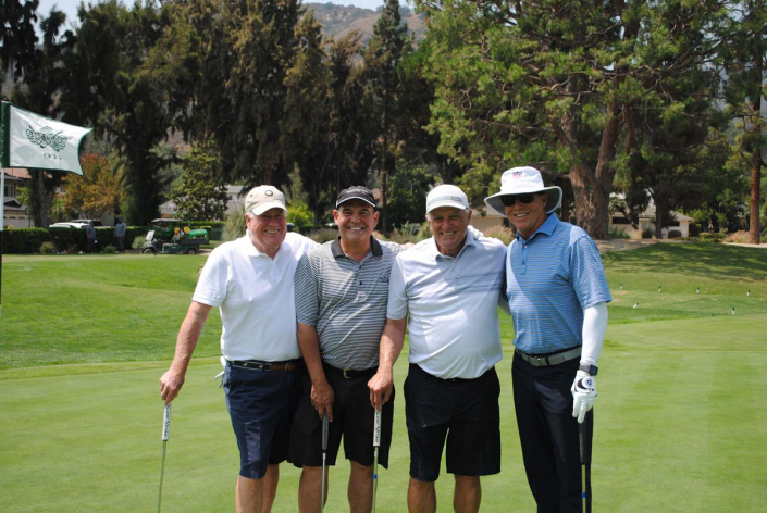 four men standing on a golf green